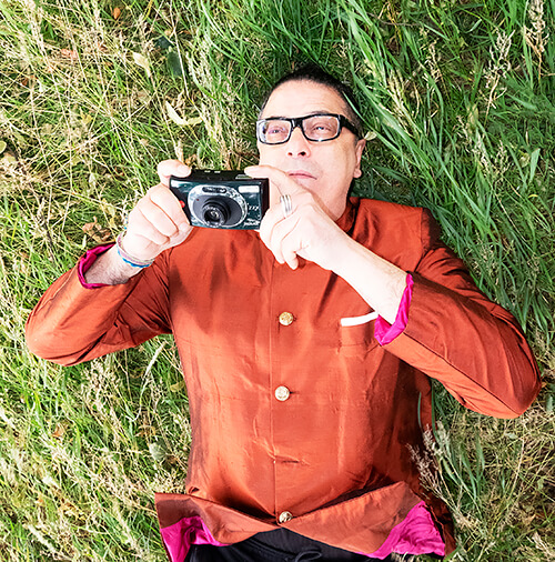 A person lying in grass holding a camera  AI-generated content may be incorrect.